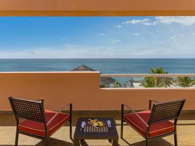 Terrassenblick auf das Meer mit zwei roten Sesseln und einem kleinen Tisch dazwischen.