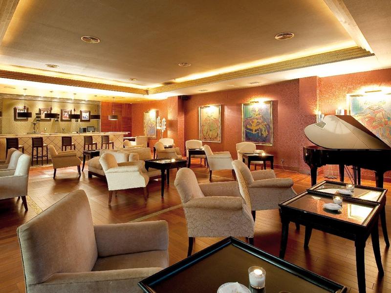 Elegante Hotel-Lounge mit bequemen Sesseln und Flügelklavier in warmem Licht.