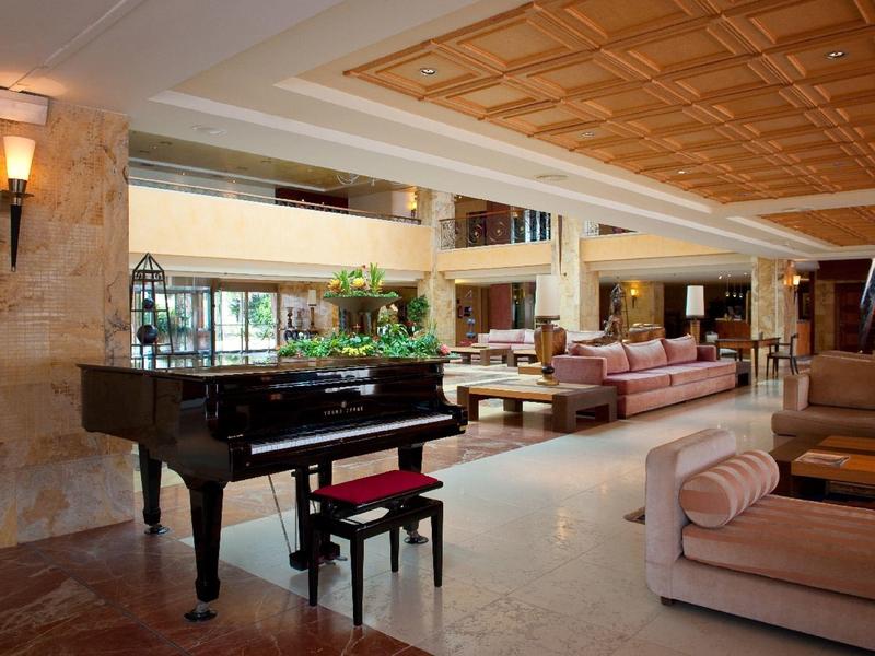Elegante Hotellobby mit Flügelklavier, bequemen Sofas und dekorativem Deckenmuster.