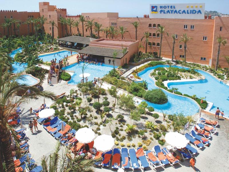 Große Hotelanlage mit Pool, Sonnenschirmen, Liegestühlen und grün bewachsenem Inselbereich.