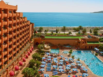 Blick auf ein Hotel mit Pool, Sonnenschirmen und direktem Zugang zum Strand am Meer.