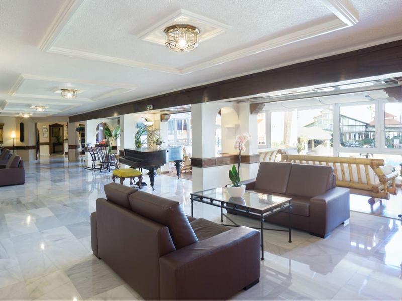 Heller, geräumiger Warteraum mit modernen braunen Sofas, Glastischen und großen Fenstern.