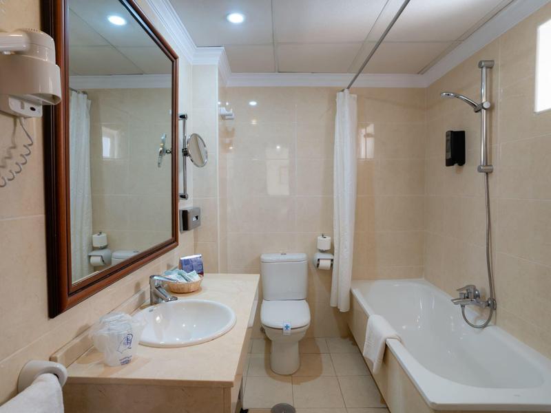 Moderne Badezimmer mit weißer Toilette, Badewanne, Waschbecken und großem Spiegel.