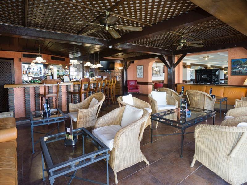 Gemütliche Lounge mit Korbsesseln, Holzmöbeln und Deckenventilatoren in warmem Farbton.