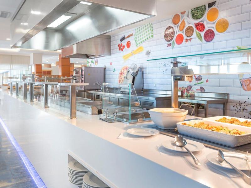 Moderne Kantine mit Buffet, hellem Ambiente und verschiedenen warmen Gerichten in großen Schalen.