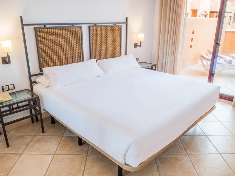 Modernes Hotelzimmer mit großem Doppelbett und Balkon mit Blick nach draußen