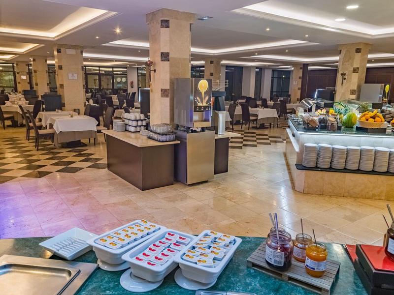 Modernes Hotelfrühstücksbuffet mit verschiedenen Speisen und Getränken in einem eleganten Speisesaal.