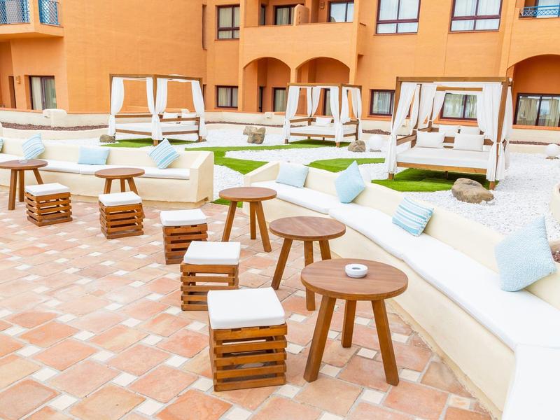 Gemütliche Sitzgelegenheiten mit Kissen und Hockern im Außenbereich eines Hotels.