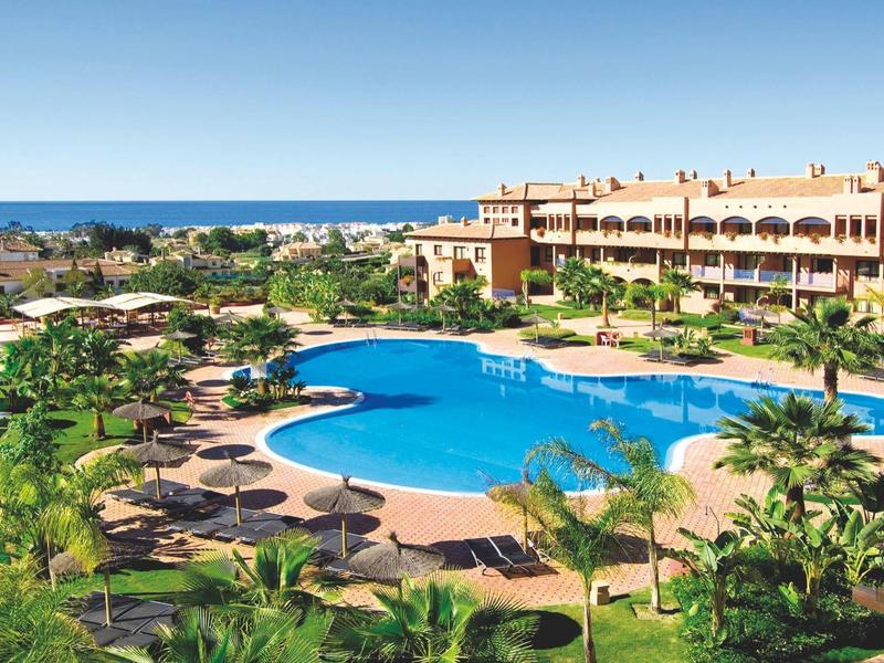 Großer Außenpool mit Liegestühlen und Sonnenschirmen in einem Hotelresort mit Meerblick.