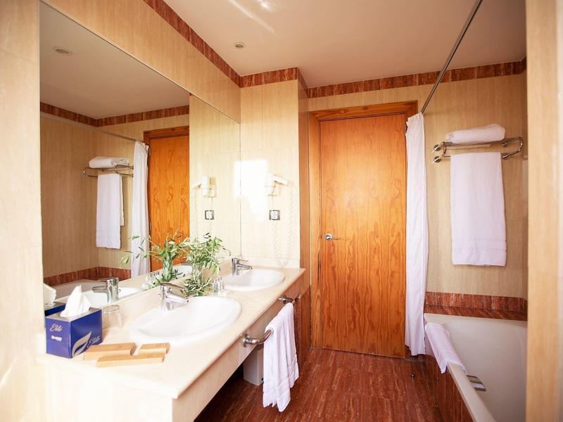 Helles Badezimmer mit großem Spiegel, Waschbecken, Holzdekor und weißen Handtüchern.