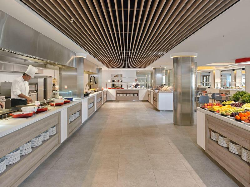 Großer Buffetbereich mit modernen Holzdecken, breiten Gängen und frischem Obst- und Gemüseangebot.