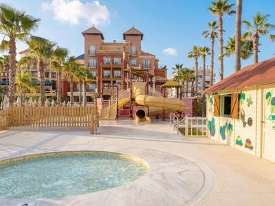 Piscina dell'hotel con vasca idromassaggio, scivoli e palme con tempo soleggiato.