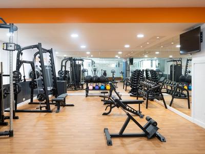 Palestra moderna con varie attrezzature e pavimento in legno in un hotel.