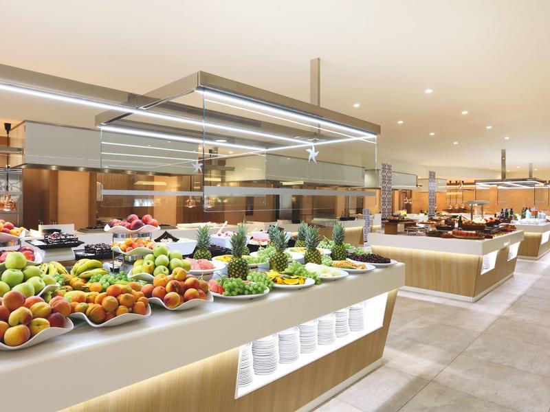 Großzügiges Buffet mit frischem Obst, Gemüse und Salaten in modern gestaltetem Restaurant.