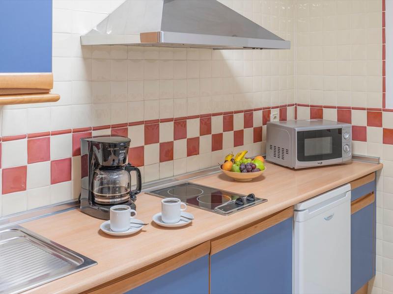 Moderne Küche mit Holzarbeitsplatte, Kühlschrank, Kaffeemaschine, Mikrowelle und Herdplatte.