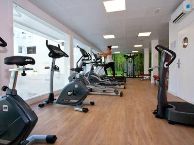 Moderner Fitnessraum mit mehreren Cardio-Geräten und großen Fenstern