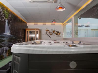 Ambiente alberghiero moderno con una grande vasca idromassaggio e decorazione murale a cascata nell'area benessere.