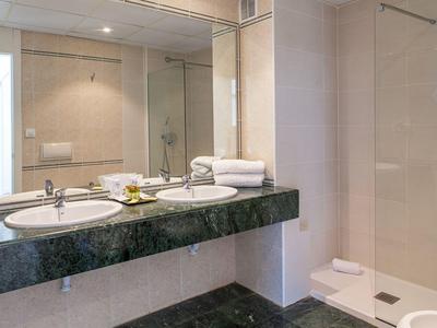 Bagno luminoso con doppi lavandini, doccia in vetro e elegante piano in marmo.