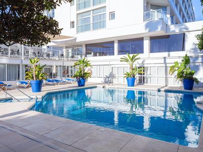Piscina exterior moderna de hotel con macetas azules y tumbonas.