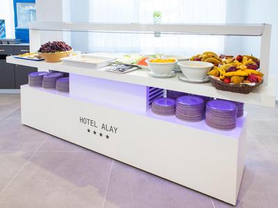 Moderner Frühstückstisch mit Obst, Süßigkeiten und Geschirr, weißer Korpus mit lila Beleuchtung.