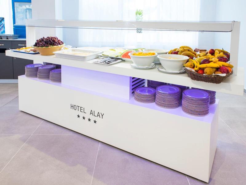 Moderner Frühstückstisch mit Obst, Süßigkeiten und Geschirr, weißer Korpus mit lila Beleuchtung.