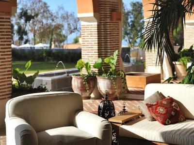 Gemütliche Terrasse mit weißen Sesseln, Pflanzen, Backsteinbögen und Blick aufs Meer.