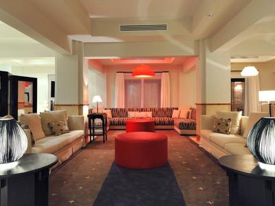 Großer Wohnraum mit beigen Sofas, runden roten Hockern und dekorativen Lampen auf schwarzen Tischen.