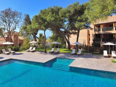 Moderner Außenpool mit blauer Wasserfläche, umgeben von Liegestühlen, Bäumen und Gebäuden.