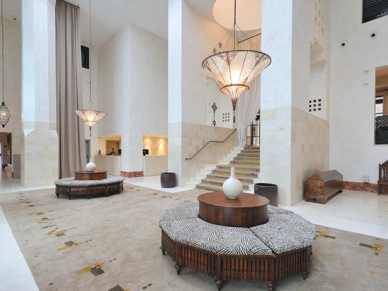 Großer heller Raum mit modernen Sesseln, hohen Wänden und eleganten Kronleuchtern.