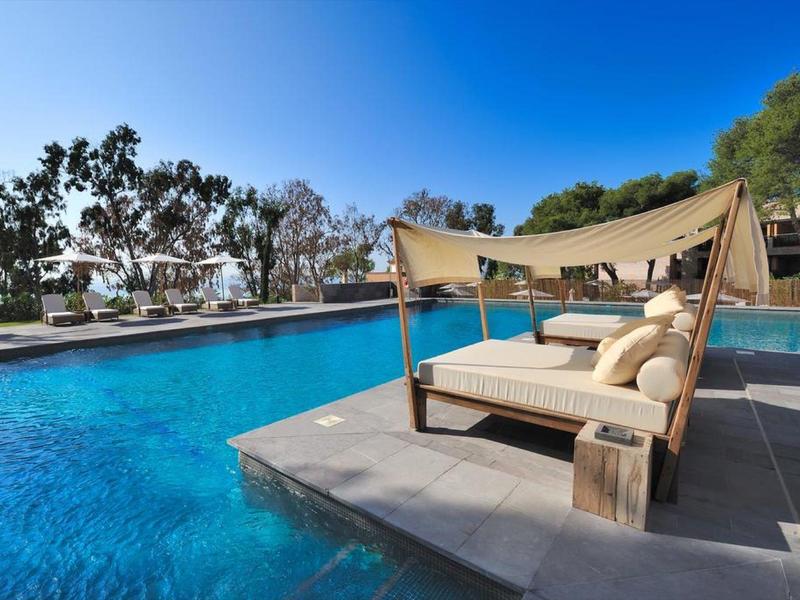 Moderner Außenpool mit blauem Wasser, Lounge-Bett und grünem Garten im Hintergrund.