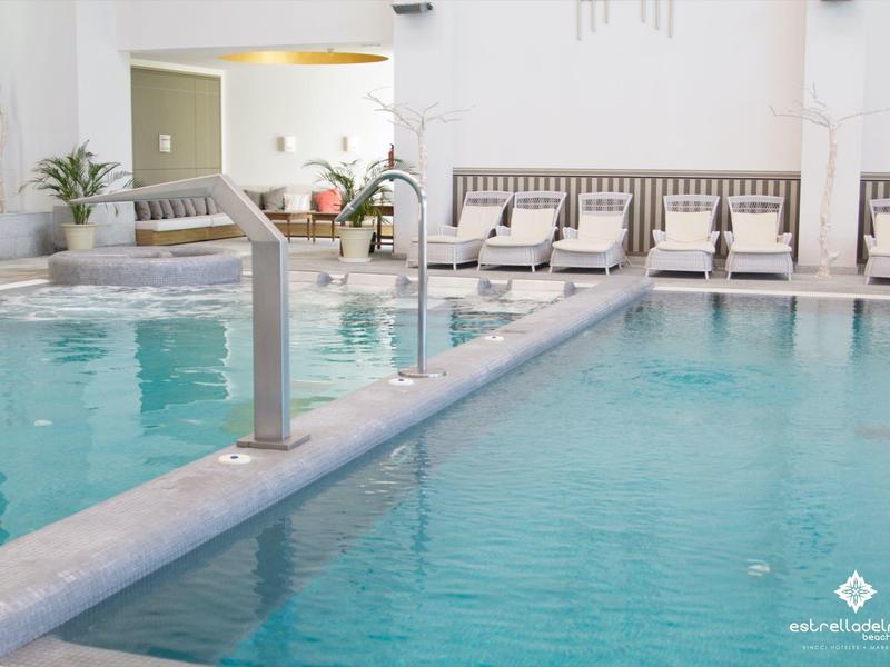 Moderner Schwimmbadbereich mit klar blauem Wasser, Liegestühlen und weißer Gestaltung.