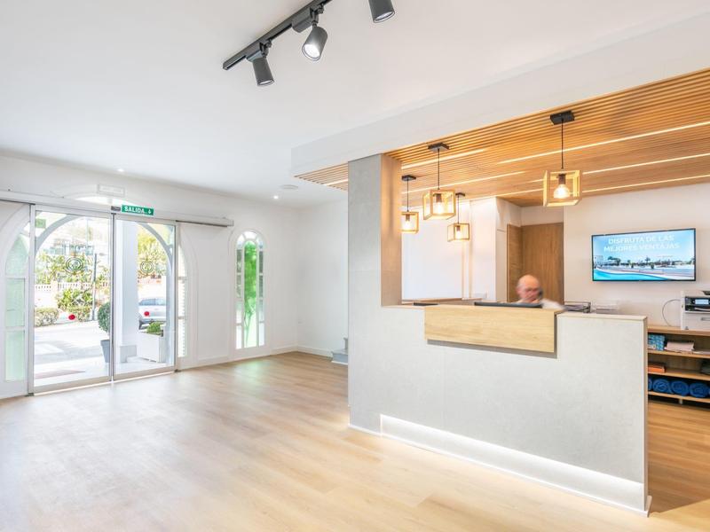 Heller Empfangsraum mit Holzfußboden, Tresen, Holzelementen und großen Fensterbögen.