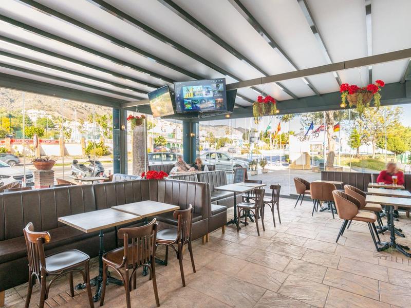 Offener Gastronomiebereich mit Tischen, Stühlen, braunen Sitzbänken und Blick auf Terrasse.