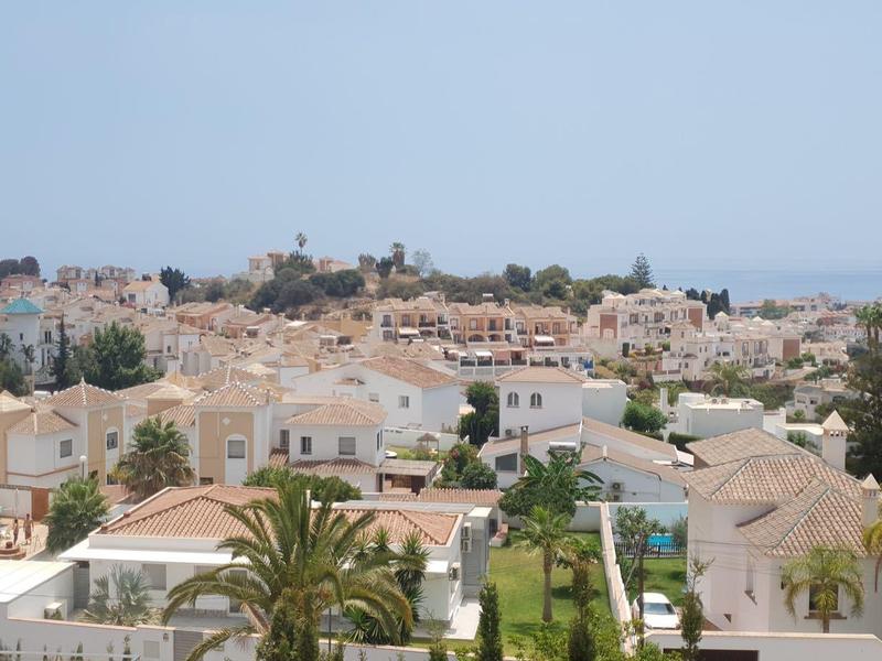 Stadt mit weißen Gebäuden, roten Dächern, Palmen und klarem Himmel im Hintergrund.