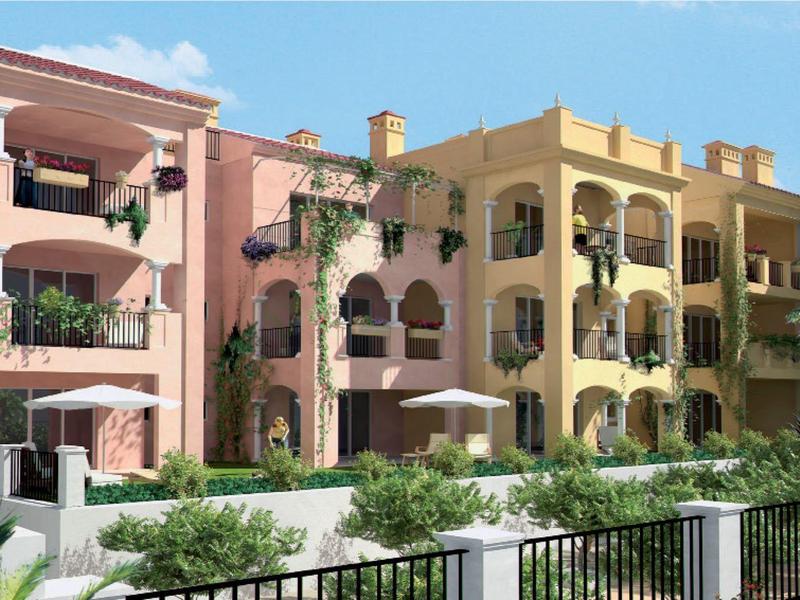 Bunte Wohnhäuser in Pastellfarben mit Balkonen, Pflanzen und blauem Himmel im Hintergrund.