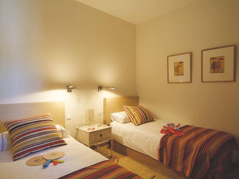 Kleines Schlafzimmer mit zwei Einzelbetten, gestreiften Decken und warmem, gedämpftem Licht.