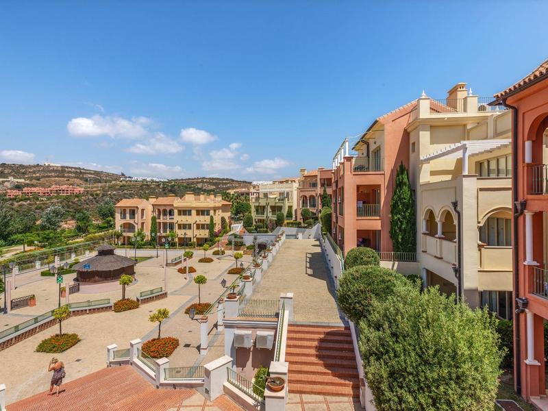 Bunte Wohnhäuser und gepflasterte Straßen mit Pflanzen unter blauem Himmel in sonniger Landschaft.