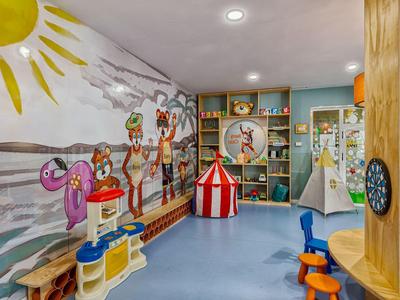 Bunter Spielraum mit Wandgemälde, Spielküche, Zelt, Regalen und bunten Kindermöbeln.