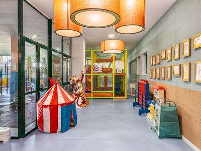 Heller, bunter Kinderspielraum mit buntem Zelt, Schaukeln und Wandbildern.