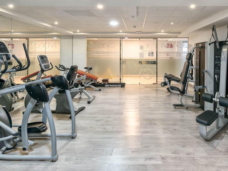 Moderne, helle Turnhalle mit Laufbändern, Kraftgeräten und glattem Holzfußboden.