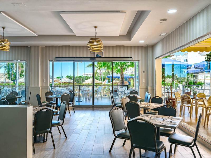 Helles Restaurant mit modernen Stühlen, Tischen und großen Fenstern mit Blick auf Terrasse und Meer.