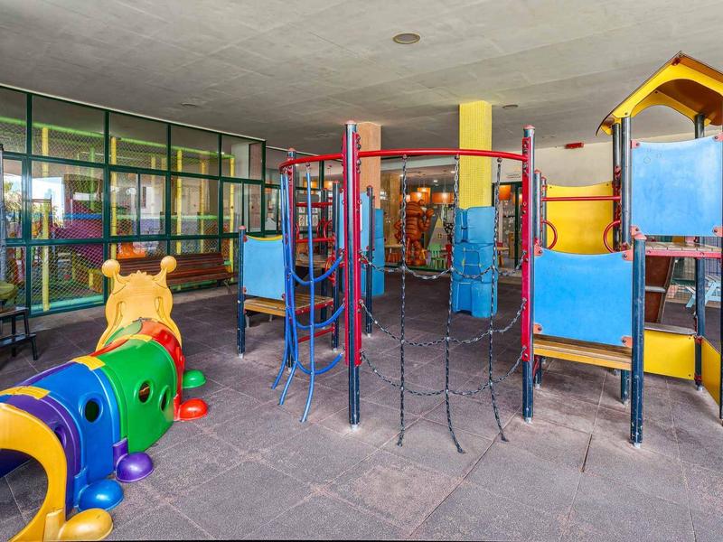 Bunter Indoor-Spielplatz mit Klettergerüst, Tunnelrutsche und Wurm-Spielgerät aus Kunststoff.