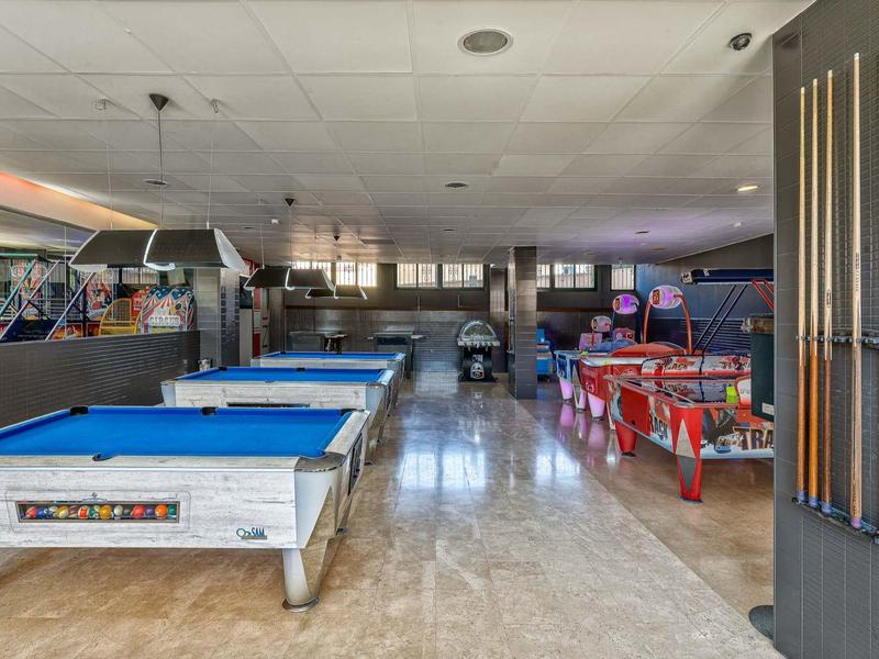 Innenraum eines Spielzentrums mit Billardtischen, Flipperautomaten und Spielautomaten.