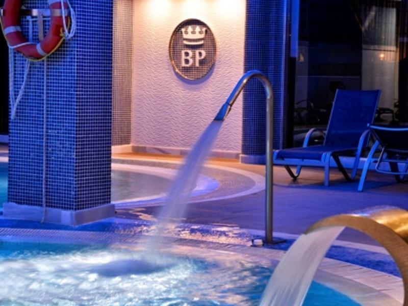 Innenpool mit blauem Licht, sprudelndem Wasser und modernen Liegestühlen.