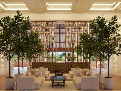 Hotel-Lobby mit Pflanzen, bequemen Sofas und warmem, einladendem Licht.