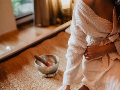 Frau im Bademantel berührt eine Massagebürste neben einem Spa-Pool.