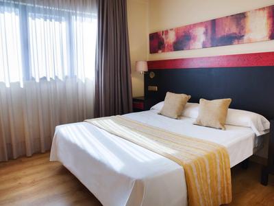 Hell eingerichtetes Schlafzimmer mit großem Bett, goldfarbenen Kissen und dekorativer Wandgestaltung.