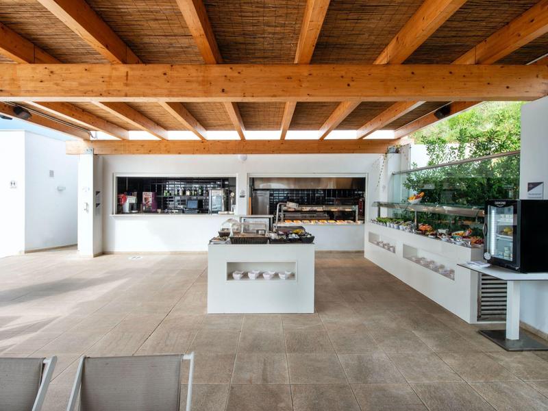 Offener Raum mit Holzdecke, moderner Kaffee- und Snackbar, weißem zentralem Tresen und hellen Wänden.