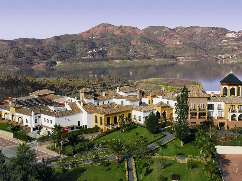 Großes Landhaus mit gelben Wänden, Terrakottadächern und Garten an See und Bergen.