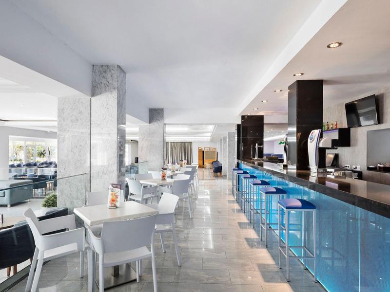 Moderner, heller Gastraum mit weißen Stühlen, blauer Bar und Marmorboden in elegantem Restaurant.